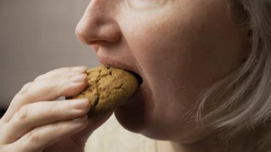 Kurabiye yiyen şişman kadın, yakın plan. Şeker bağımlılığı, aşırı yeme. Yemek bağımlılığı ve diyet konsepti. Yan görünüm