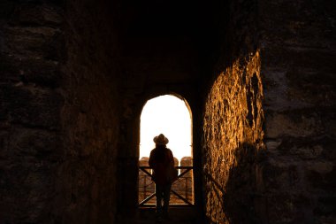 Genç kadın Ukrayna 'daki eski kalenin kemerinde duruyor, Akkerman. Gün batımındaki kız silueti. Boşluğu kopyala