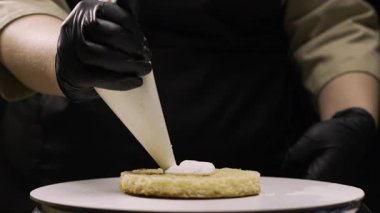 Adım adım muz dolgulu benta keki yapmak. Pasta şefi, kek poşetindeki krem peyniri, tezgahtaki ilk pasta katmanına dikkatlice sıkıştırır. Adım üç..