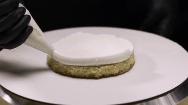 Adım adım muz dolgulu benta keki yapmak. Pasta şefi, tezgahtaki ilk pasta katmanında krema oğlundan bir sınır yaratıyor. Beşinci adım.