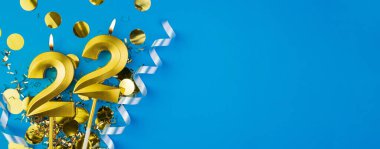 22 yılı kutluyoruz. Kutlamanın mavi arka planında ışıltılı bir şekilde yatan yirmi iki numaralı altın yanan mum. Kopyalama alanı olan bayram afişi.