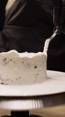Pasta hazırlayan pastacı, beyaz kremayı spatulayla kaplayan ve lezzetli bir tatlı yapan kişi. Dikey video