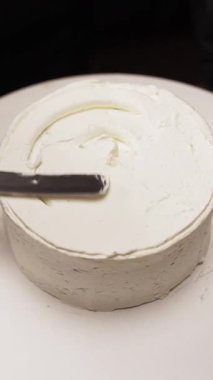 Pasta şefi krema koymak için spatula kullanarak pasta yapıyor. Yakın plan. Dikey video