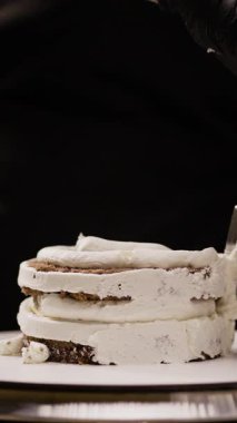 Bir pastanede pasta yapıp dekore etmek. Pasta şefinin, yanında spatulayla kremalı pasta yaparken yakın plan fotoğrafı. Dikey video