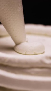 Kremalı pasta yapma süreci. Pasta şefi kremalı kek tabakasına krema sıkıyor. Dikey video