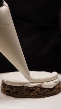 Şekerlemecinin yakın çekimi küçük pastayı pasta poşetindeki beyaz kremayla kaplıyor. Küçük işletme kavramı