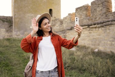 Genç bayan turist, antik kalede akıllı telefon kullanarak selfie portresi yapıyor. Seyahat ve turizm kavramı