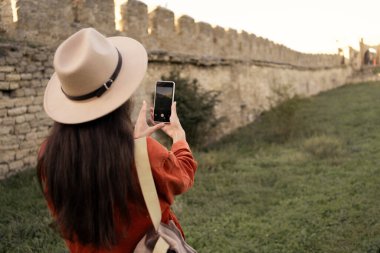 Şapkalı genç bir turistin, Ukrayna 'daki ortaçağ kalesini ziyaret ederek fotoğraf çekmesini. Yakın plan.