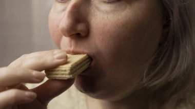 Şeker tüketimi ve sağlıksız gıda kavramı. Şişman, aç bir kadın tatlı waffle yiyor, yakın plan. Yan görünüm