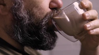 Çikolatalı süt ya da cam bardaktan kakao içen genç adam, yakın plan. Yan görünüm