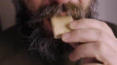 Sakallı adamı yakından çekerken waffle yemekten zevk alır. Yakın plan.