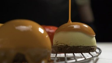 Mini cheesecake 'in üzerine karamelli jöle dökülüyor ya da çikolatalı kremalı kek, profesyonel pasta mutfağında gurme tatlı hazırlama, tatlıya düşkünlük kavramı.
