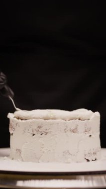Şekerleme ustalıkla pasta katmanlarına spatula kullanarak krema yayar, hamur işi mutfağındaki doku ve tasarımı mükemmelleştirir, profesyonel tatlı yapma tekniklerini sergiler.