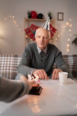 Orta yaşlı bir adam doğum günü pastasında mum yakarken, yaşlı babası, emekli olmuş, evinde sıcak ve samimi bir aile kutlaması yaparak dilek tutmaya hazırlanıyor..