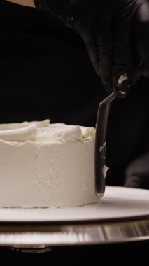 Şekerleme pürüzsüz, üzerinde spatula ve yanında krema olan bir pasta. Adım adım pasta yapma süreci ayrıntılı şekerleme ve dekorasyonu gösterir.