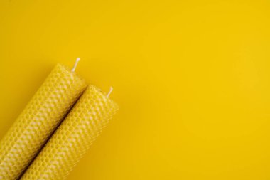 Parlak sarı yüzeyde iki balmumu mum. Düz Yat. Yakın plan. Boşluğu kopyala