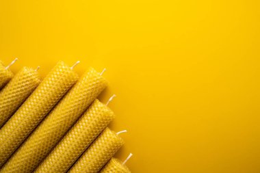 Cesur sarı arka planda doğal balmumu mumları. Düz Yat. Boşluğu kopyala
