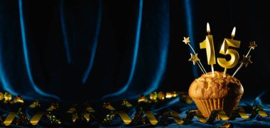 15. yaş günü partisi yaklaşıyor. Kadife mavisi arka planda on beş numaralı mumu olan çikolatalı kek. Pankart, metin için boşluk.