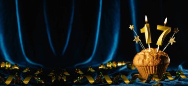 Yaş partisi 17. yaş gününde. Kadife mavisi arka planda on yedi numaralı mumu olan çikolatalı kek. Pankart, metin için boşluk.