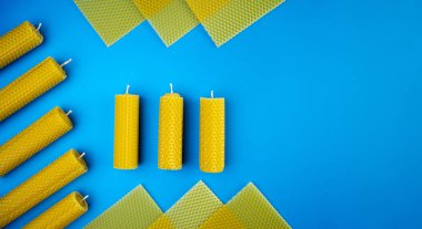 Dekoratif balmumu mumları mavi arka planda bal aromalı, gözenekli balmumu çarşaflı. Üst görünüm