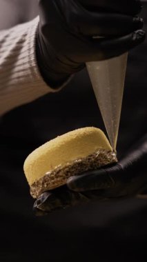 Pastanedeki kremalı pastayı süslemek için hamur işi torbası kullanan, güzel görünümü için krema ekleyen, tatlıyı lezzetli ve güzel yapan, mutfakta dikkatli bir şekilde çalışan şekerlemecinin yakın çekimi..