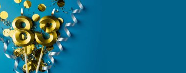 83 'üncü yıl kutlaması. Mavi arka planda konfetili 83 numaralı altın yanan mumlar, kopyalama alanı. Selamlama pankartı.