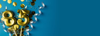 85 yıllık kutlama. Mavi arka planda konfetili 85 numaralı altın yanan mumlar, kopyalama alanı. Selamlama pankartı.
