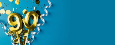 90 yıllık kutlama. Mavi arka planda doksan numaradan yanan altın mumlar konfetili, kopyalama alanı. Selamlama pankartı.