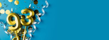 93 yıllık kutlama. Doksan üç numaralı altın yanan mumlar mavi arka planda, konfetili, kopyalama alanı. Selamlama pankartı.