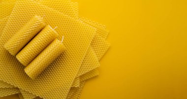 Doğal balmumu. Sarı arka planda balmumu çarşafların üzerinde duran el yapımı mumlar. Boşluğu kopyala