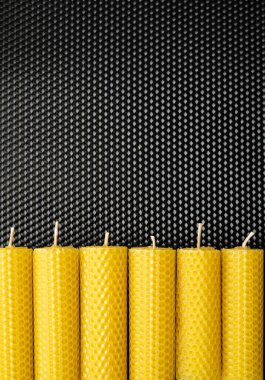 El yapımı sarı balmumu mumlar siyah desenli arka plan ya da balmumu örtüsü, doğal ve organik dekor, çevre dostu ürünler, mum yapımı ve sürdürülebilirlik kavramı üzerine düzenlenmiştir.