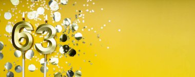 Altmış üç yıllık doğum günü. 63 numaralı altın kutlama mumu. Sarı renkli arka plan. Doğum günü ya da yıldönümü kutlaması kavramı. Pankart. Boşluğu kopyala