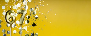 Altmış yedi yıllık doğum günü. 67 numaralı altın kutlama mumu. Sarı renkli arka plan. Doğum günü ya da yıldönümü kutlaması kavramı. Pankart. Boşluğu kopyala