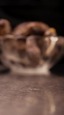 Kapalı kapılar ardında cam kaseden dökülen hurmalar, vejetaryen tatlılar ve diyet gıda konsepti. Yakın plan. Üst görünüm