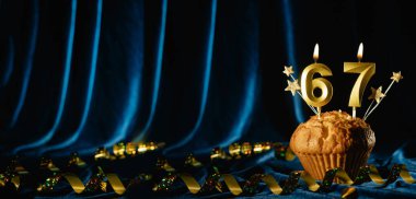 67 numaralı altın kutlama mumu ve küçük yıldızlar parlak mavi kadife arka planda tatlı kek içinde. Doğum günü ve yıldönümü kutlaması kavramı. Pankart. Boşluğu kopyala.