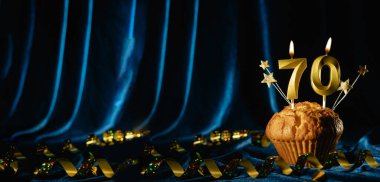 70 numaralı altın kutlama mumu ve küçük yıldızlar parlak mavi kadife arka planda tatlı kek içinde. Doğum günü ve yıldönümü kutlaması kavramı. Pankart. Boşluğu kopyala.