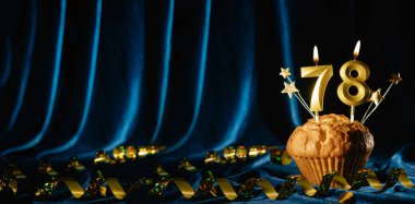 78 numaralı kutlama mumu ve parlak mavi kadife arka planda tatlı kek içinde küçük yıldızlar. Doğum günü ve yıldönümü kutlaması kavramı. Pankart. Boşluğu kopyala.