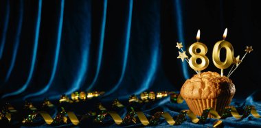 80 numaralı kutlama mumu ve küçük yıldızlar parlak mavi kadife arka planda tatlı kek içinde. Doğum günü ve yıldönümü kutlaması kavramı. Pankart. Boşluğu kopyala.