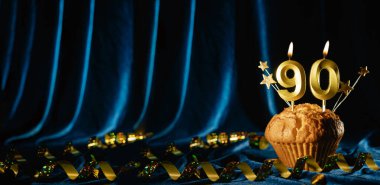 90 numaralı altın kutlama mumu ve küçük yıldızlar parlak mavi kadife arka planda tatlı kek içinde. Doğum günü ve yıldönümü kutlaması kavramı. Pankart. Boşluğu kopyala.