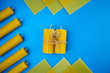 Sarı el yapımı balmumu mumlar iple bağlanmış mavi arka planda diğer mumların etrafında uzanır, üst manzara, düz uzanma