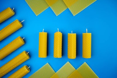 El yapımı balmumu mavi arka planda farklı mumlar. Vejetaryen mumu ve doğal malzemeler. Düz yatış, üst görünüm