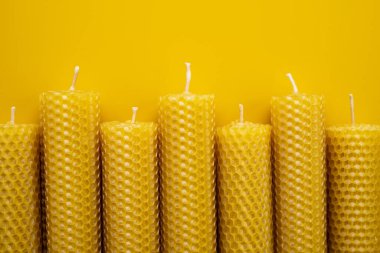 Canlı sarı arka planda el yapımı balmumu mumları. Düz Yat. Yakın plan.