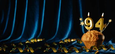 94 numaralı altın kutlama mumu ve küçük yıldızlar parlak mavi kadife arka planda tatlı kek içinde. Doğum günü ve yıldönümü kutlaması kavramı. Pankart. Boşluğu kopyala.