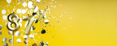 Seksen yedi yıllık doğum günü. 87 numaralı altın kutlama mumu. Sarı renkli arka plan. Doğum günü ya da yıldönümü kutlaması kavramı. Pankart. Boşluğu kopyala.