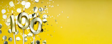Yüz yıllık doğum günü. 100 numaralı altın kutlama mumu. Sarı renkli arka plan. Doğum günü ya da yıldönümü kutlaması kavramı. Pankart. Boşluğu kopyala.