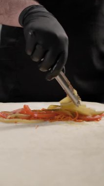 Fast food Cafe 'de et shawarma yapan şefin yakın plan çekimi. Lavaş dolduruyor. Adım adım sokak yemek hazırlığı. Dikey video