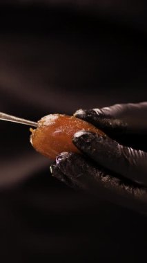 Şekerci, meyveyi vejetaryen tatlısına hazırlamak için olgun bir tarihten çukuru kaldırır. Yakın plan. Dikey video