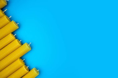 Balmumu mumları parlak mavi arka planda köşegen şeklinde dizilmiş. Dokulu yüzey doğal detayları vurguluyor. Pankart. Boşluğu kopyala