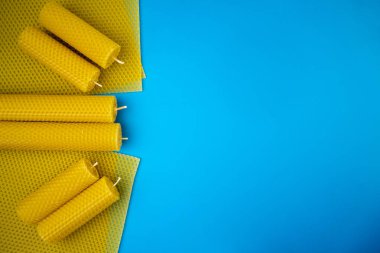 Sarı balmumu mumlar parlak mavi arka planda kumaşlarda sergilenerek doğal ve çevre dostu cazibelerini sergiliyorlar. Sürdürülebilir ürünleri desteklemek için ideal