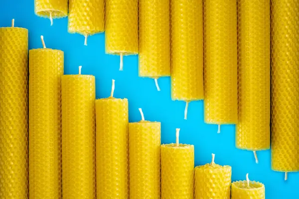 Bal peteği desenli balmumu mumları parlak mavi bir yüzeye dizilir, canlı sarı renkleri ve eşsiz dokuları sergilenir. Ev dekorasyonu ve doğal estetik için mükemmel..
